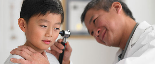 Asian doctor examining a child's ears