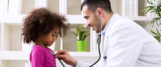 Doctor using stethoscope to listen to child's heart
