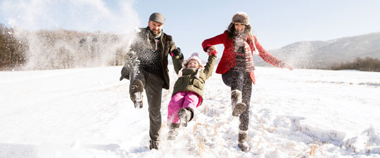 family playing in the snow with young daughter