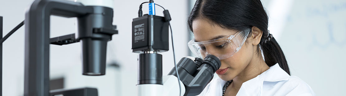 Female researcher looking through a microscope